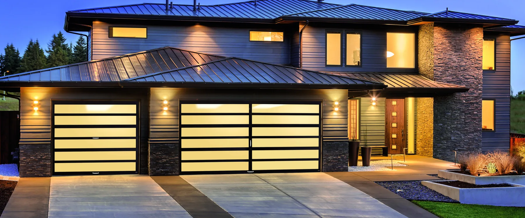 Amarr Horizon garage door in dark bronze with frost glass on a modern home at dusk