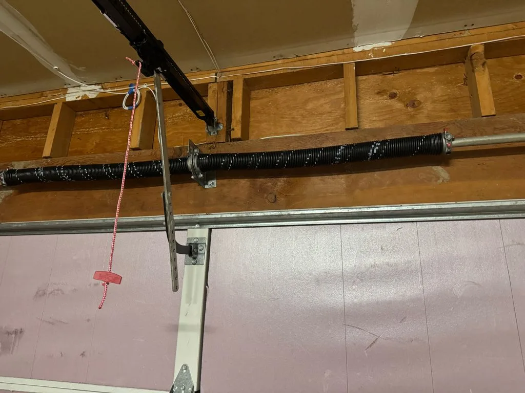New black torsion spring installed above a garage door in a Renton home