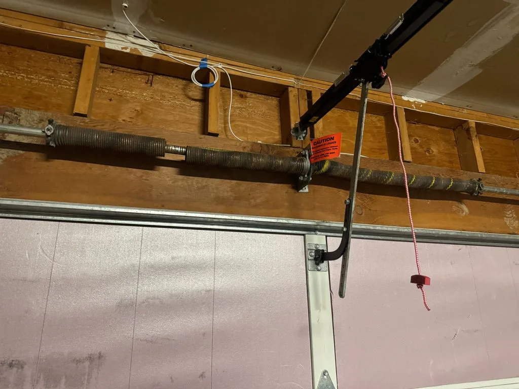 Old rusted torsion spring above a garage door in a Renton home